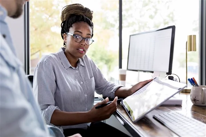Woman working at a desk with two screens and a tablet