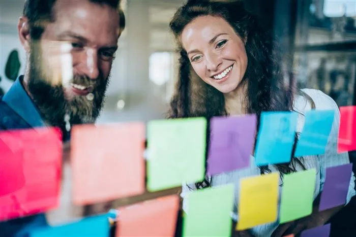 Two colleagues planning with sticky notes on a glass wall