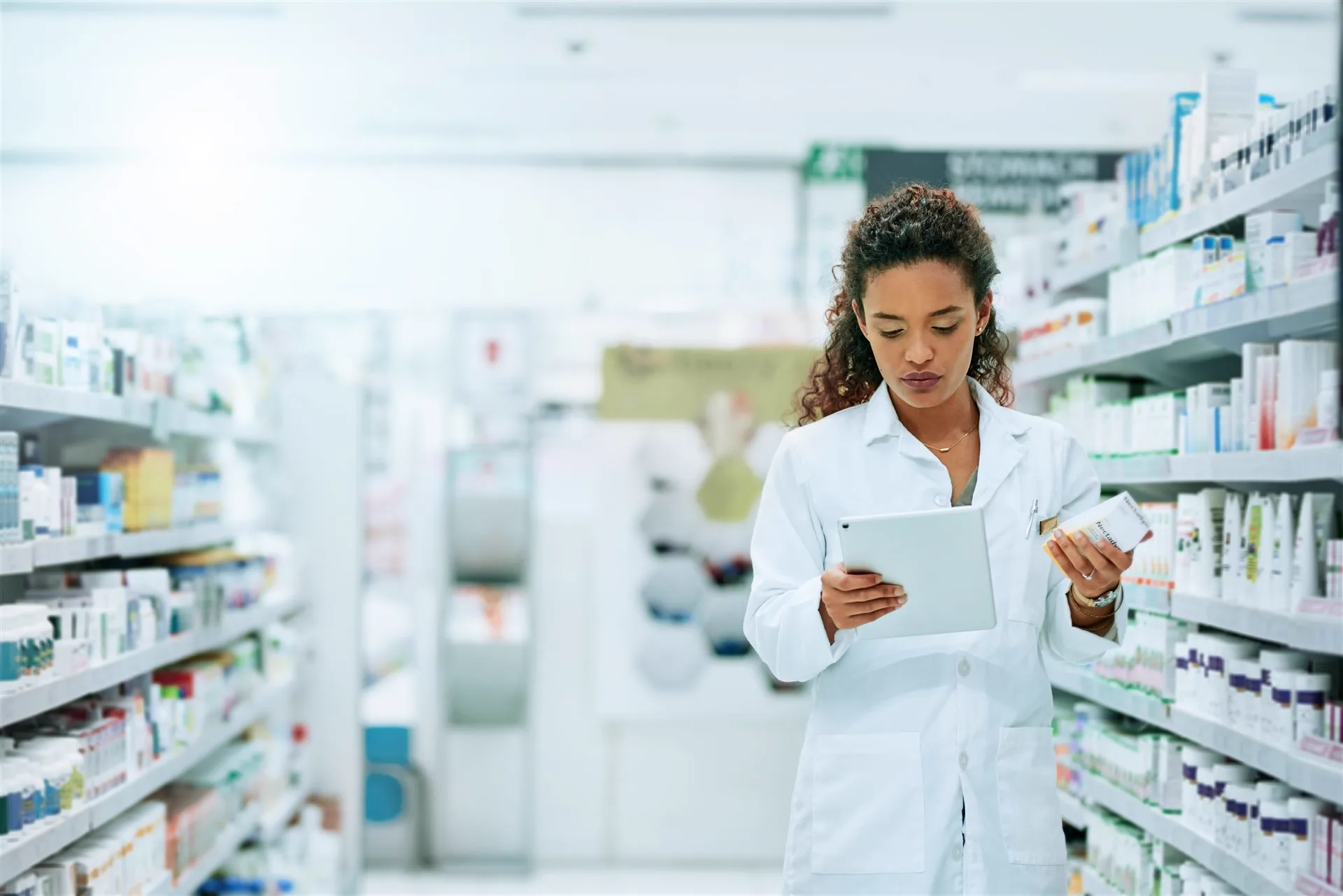 Pharmacist checking stock on shelves with a tablet