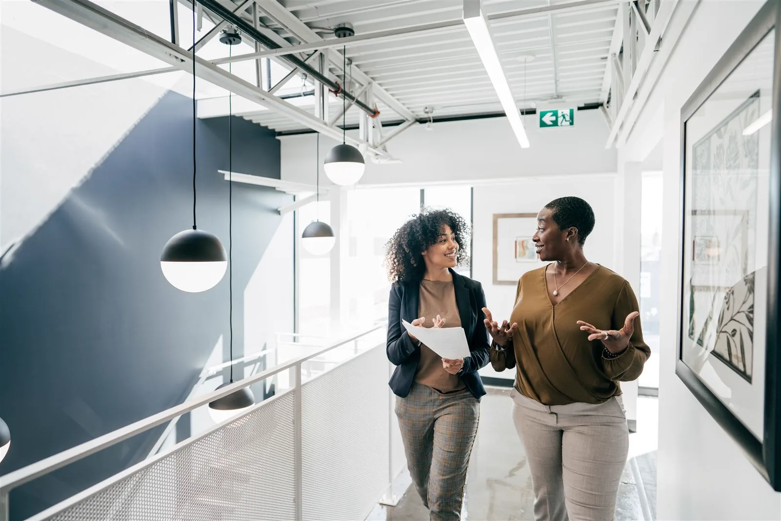Two colleagues walking through an office discussing papers