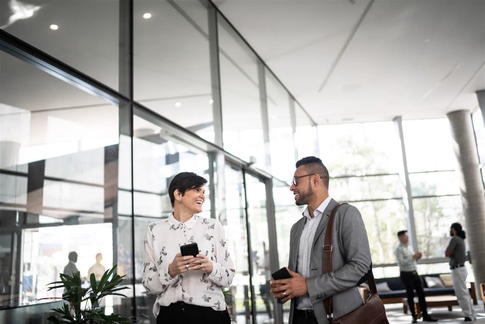 Two professionals talking in a glass-walled office