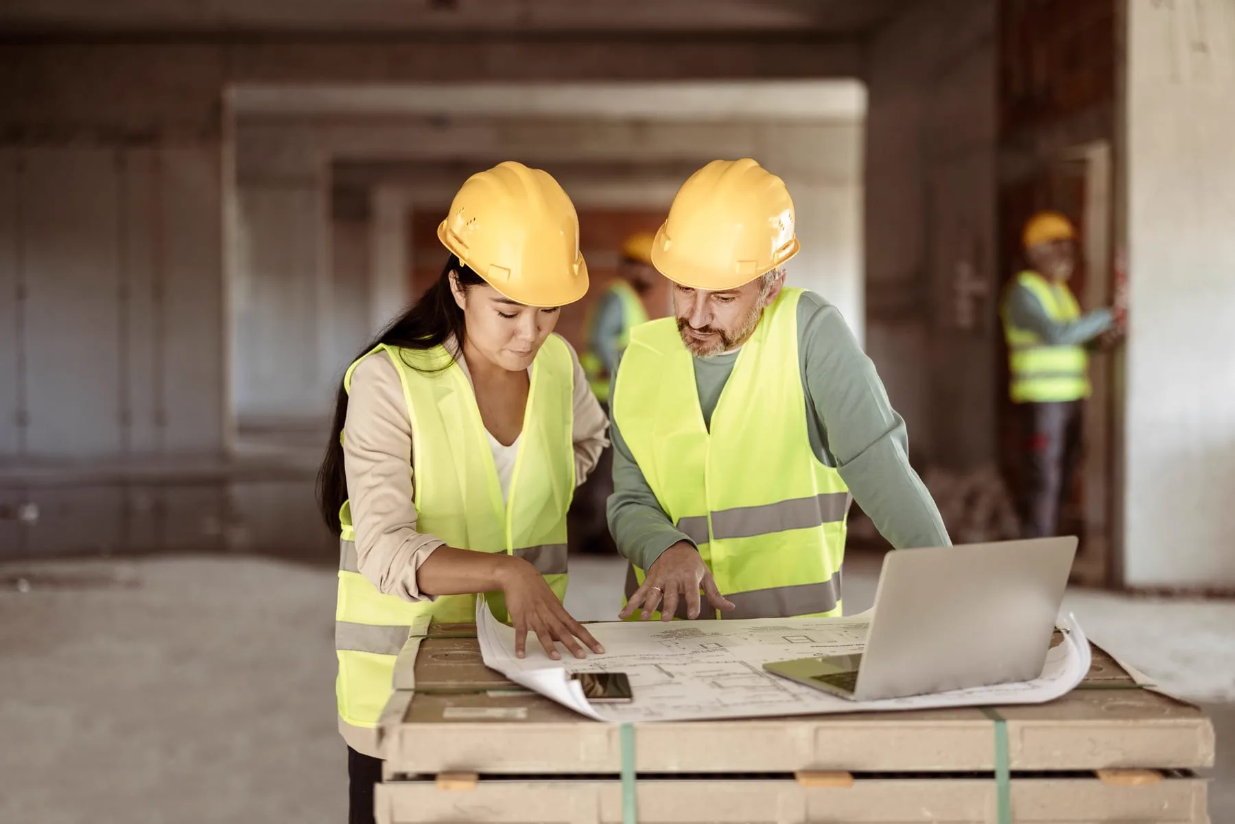 Construction professionals reviewing plans and a laptop on site